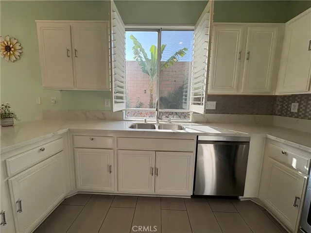 a kitchen with a sink white cabinets and a window
