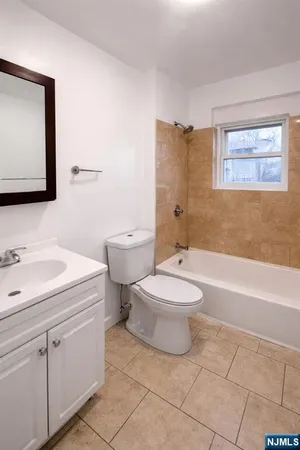 a bathroom with a toilet sink vanity tub and mirror