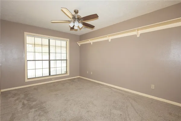 an empty room with a window and a fan