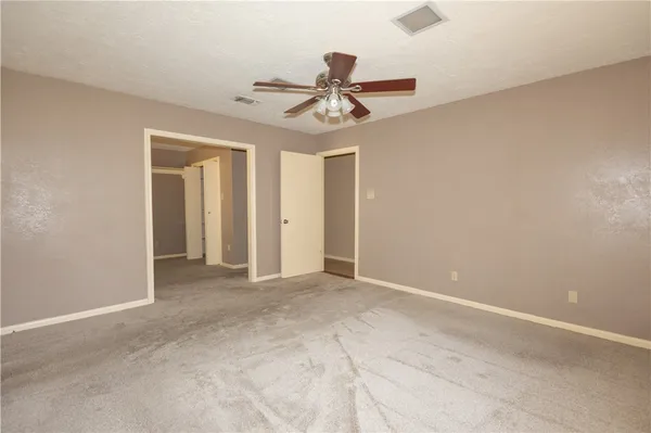 an empty room with closet and a chandelier fan