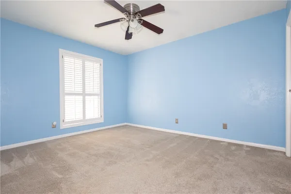 an empty room with window and ceiling fan