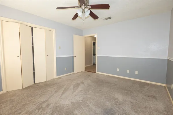 a view of an empty room and chandelier fan