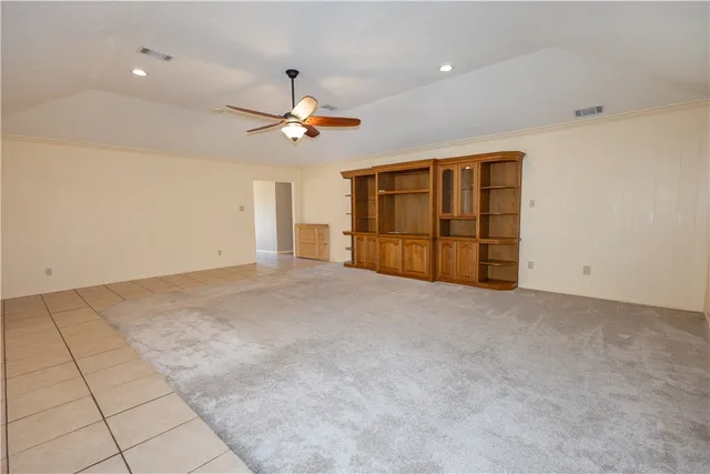 a view of a livingroom with a chandelier fan and kitchen view