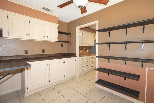 a kitchen with white cabinets and window