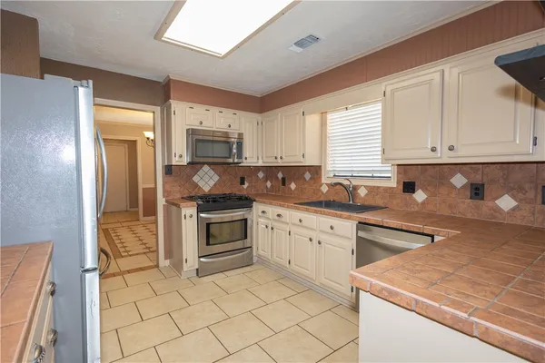 a kitchen with stainless steel appliances granite countertop a stove a sink and a microwave