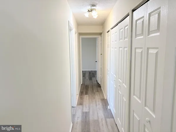 a view of a hallway with wooden floor and a bathroom