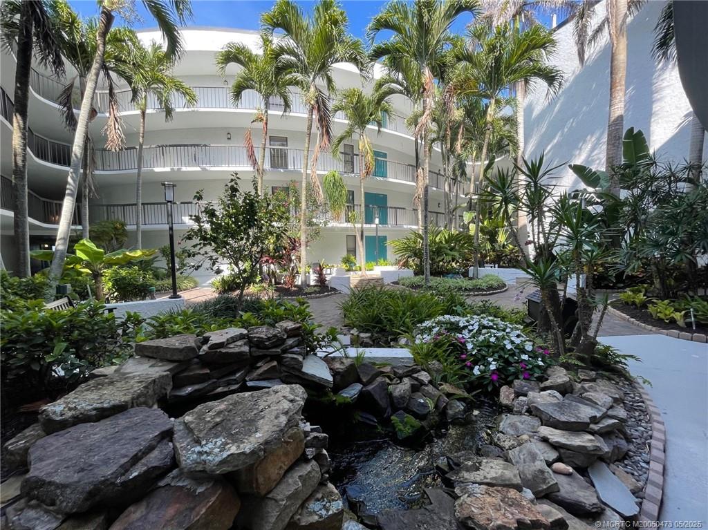 1357 Northeast Ocean Boulevard, Unit 106 Stuart, FL 34996 - Photo 3 of 38 a view of backyard of multi story residential apartment building with yard and outdoor seating