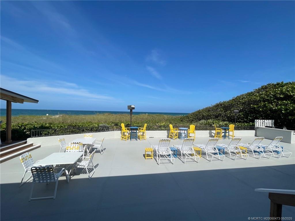 1357 Northeast Ocean Boulevard, Unit 106 Stuart, FL 34996 - Photo 32 of 38 a view of a patio with dining table and chairs under an umbrella