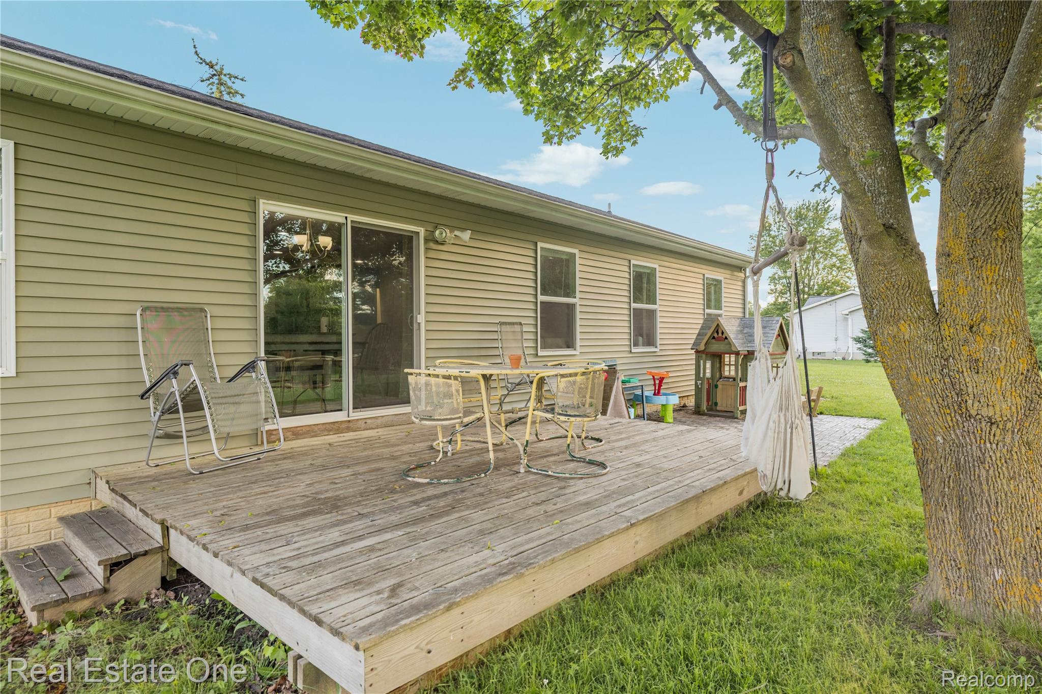 Expansive wood deck with stairs, featuring a sliding glass door entry to the interior, and a light green siding exterior