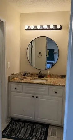 a bathroom with a granite countertop sink and a mirror