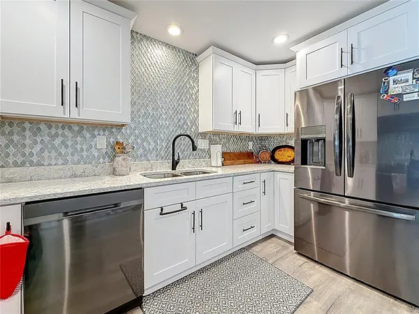 a kitchen with stainless steel appliances granite countertop a refrigerator and a stove top oven