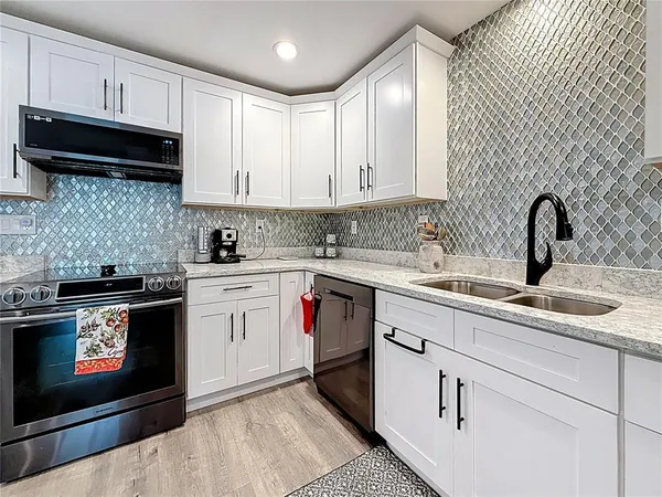a kitchen with stainless steel appliances a stove a sink and white cabinets