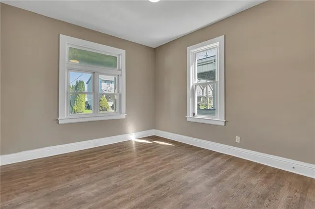 a view of an empty room with window and wooden floor