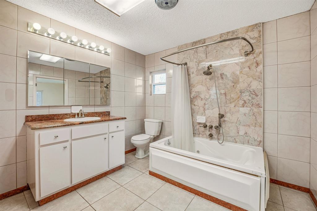 216 Broken Arrow Comanche, TX 76442 - Photo 21 of 38 a bathroom with a granite countertop sink a toilet a mirror and shower