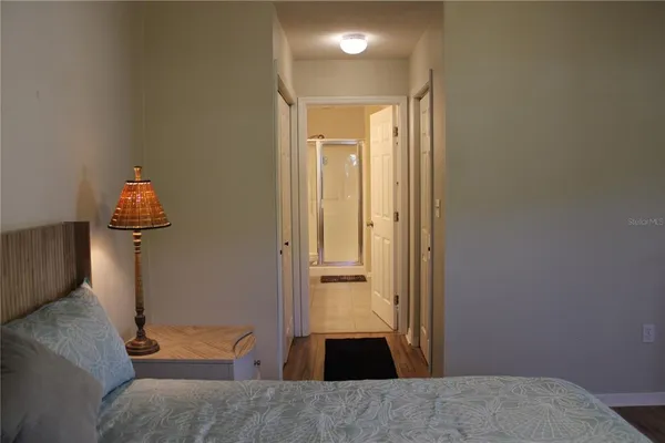 a view of a hallway to a room with wooden floor and a bathroom