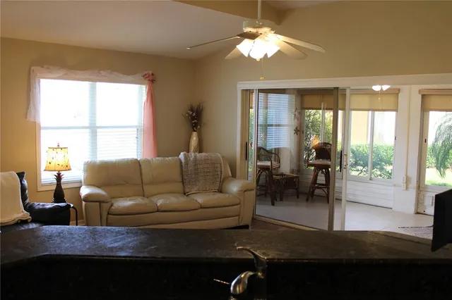 a living room with furniture a ceiling fan and a large window