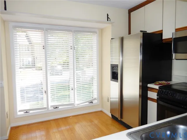 a view of a kitchen with refrigerator and wooden floor