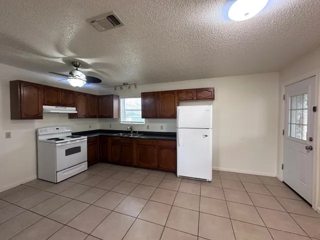 a large kitchen with a stove top oven a sink dishwasher and a refrigerator with wooden floor