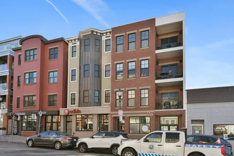 a front view of building with lot of cars and trees