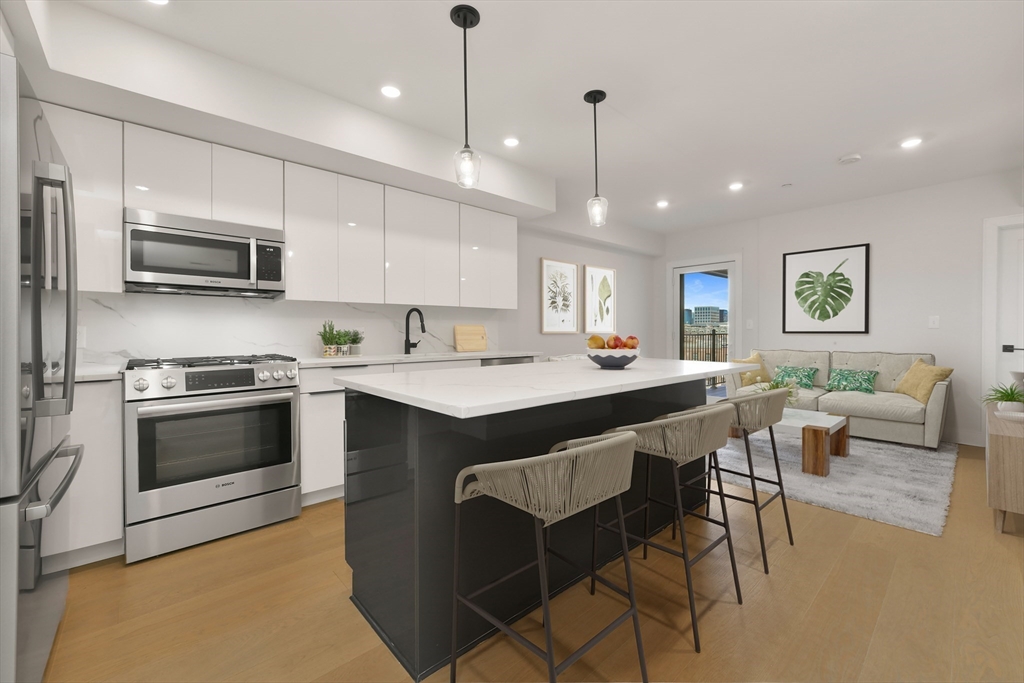 321 West Broadway, Unit 6 Boston, MA 02127 - Photo 2 of 20 a kitchen with stainless steel appliances granite countertop a stove a sink a microwave a refrigerator and white cabinets with wooden floors