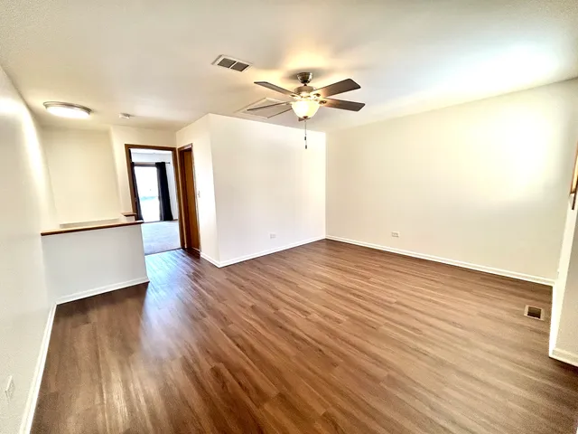 a view of a room with wooden floor and a ceiling fan