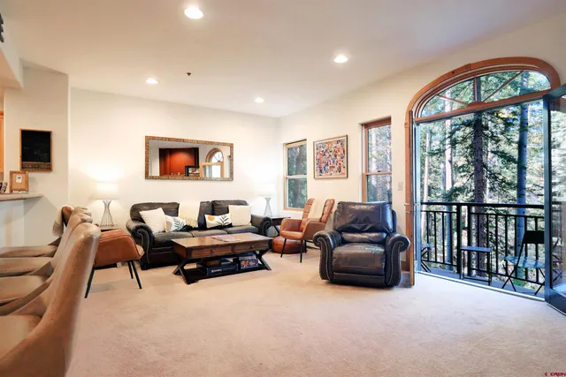 a kitchen with stainless steel appliances kitchen island granite countertop a dining table chairs and a refrigerator