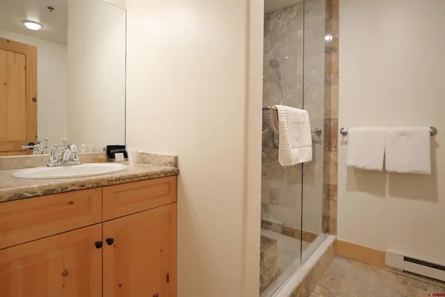 a bathroom with a granite countertop sink a mirror a vanity and a shower