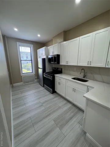 a kitchen with granite countertop a stove top oven a sink dishwasher and a refrigerator with wooden floor