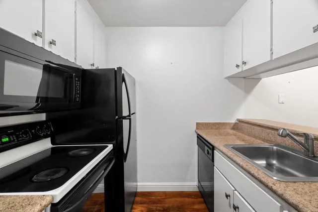 a kitchen with granite countertop a refrigerator stove and sink