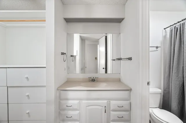 a bathroom with a granite countertop sink a toilet and a mirror