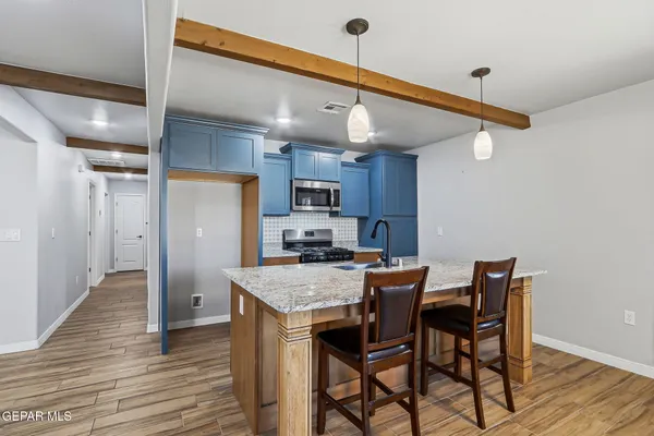 a kitchen with stainless steel appliances granite countertop a kitchen island a hardwood floor and chairs