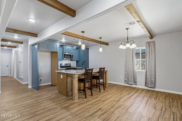a kitchen with stainless steel appliances a dining table chairs and wooden floor