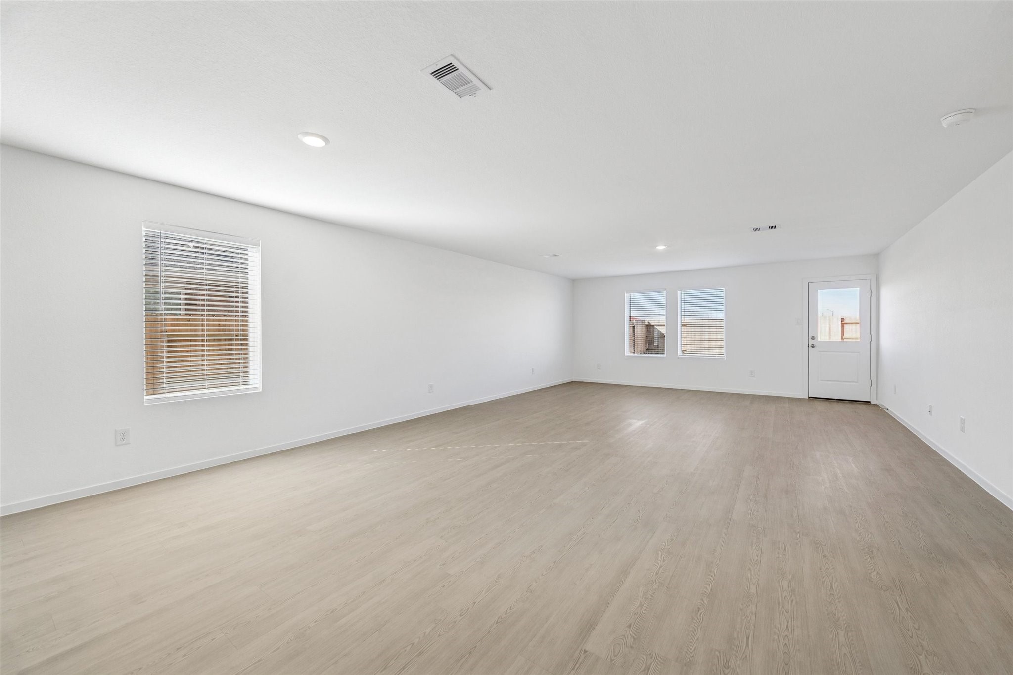 16207 Rustic Prairie Drive Hockley, TX 77447 - Photo 2 of 11 Expansive main living area boasts wide plank flooring, crisp white walls, recessed lighting, and an abundance of natural light from multiple windows.