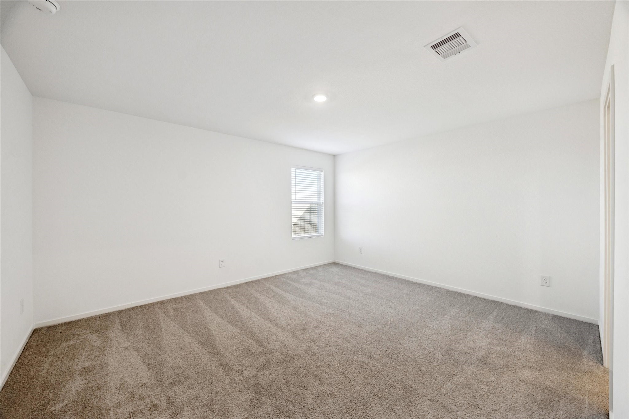 16207 Rustic Prairie Drive Hockley, TX 77447 - Photo 7 of 11 Spacious and serene, this secondary bedroom features soft carpeting, a wide layout, and ample natural light—perfect for a guest suite or shared space.