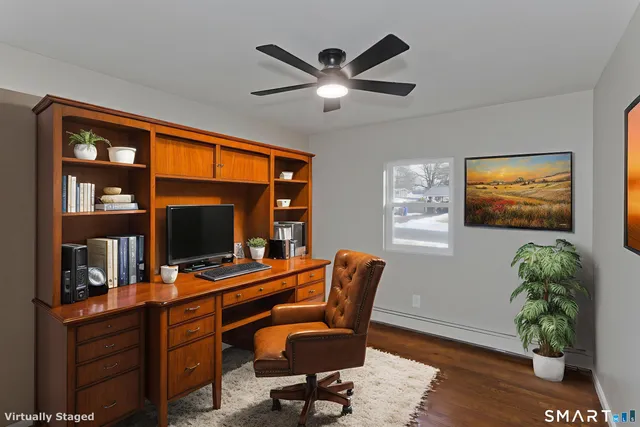 a view of an empty room with wooden floor and a ceiling fan
