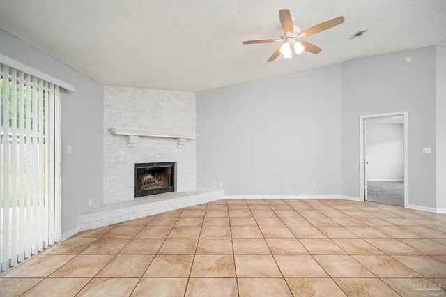 a view of an empty room with window and chandelier fan