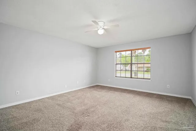 an empty room with a window and a fan