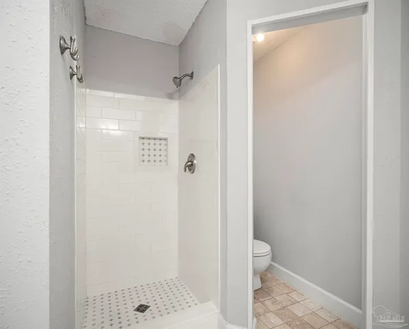 a bathroom with a granite countertop shower and a toilet