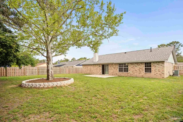a view of a house with a yard and a large tree