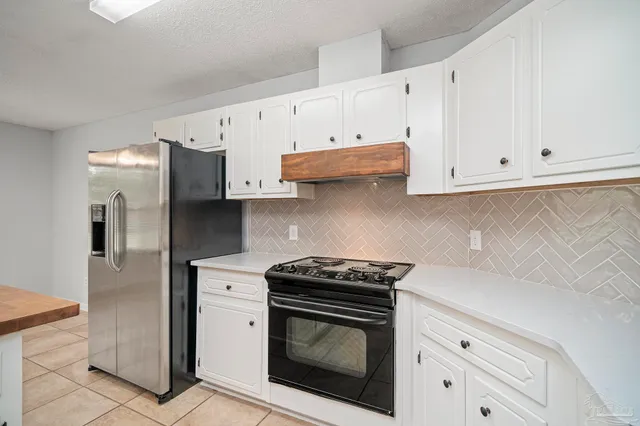 a kitchen with stainless steel appliances granite countertop white cabinets and a stove