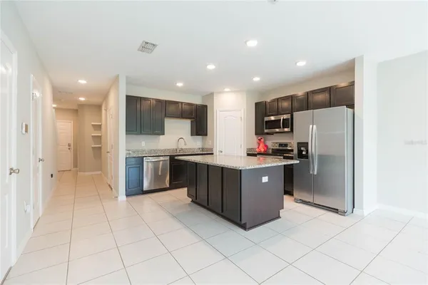 a large kitchen with stainless steel appliances kitchen island granite countertop a refrigerator and a stove top oven