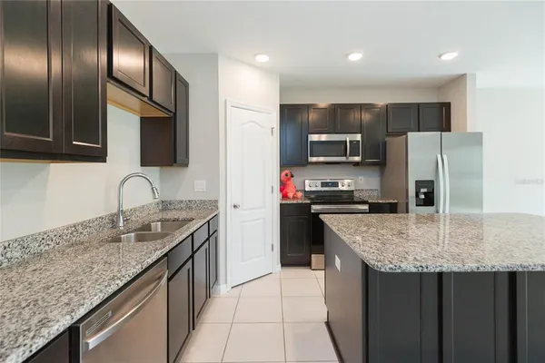 a kitchen with granite countertop stainless steel appliances a sink stove and refrigerator