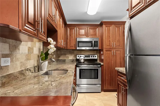a kitchen with stainless steel appliances granite countertop a refrigerator a stove and a sink with wooden floor