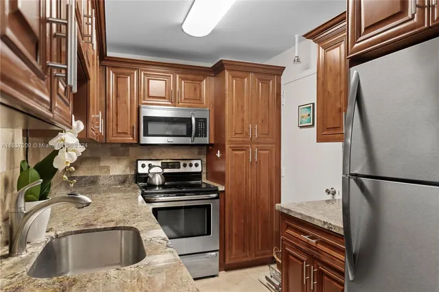 a kitchen with granite countertop a refrigerator and a stove top oven