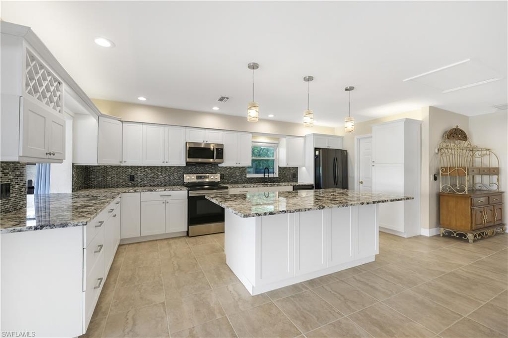 3461 Lakeview Drive Naples, FL 34112 - Photo 14 of 32 a kitchen with stainless steel appliances kitchen island granite countertop a stove top oven a sink a counter top space and cabinets