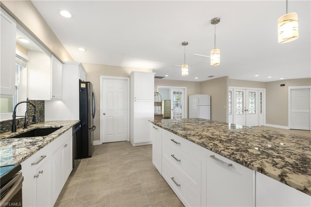 3461 Lakeview Drive Naples, FL 34112 - Photo 15 of 32 a large kitchen with kitchen island a sink granite counter tops a stove a refrigerator and a sink