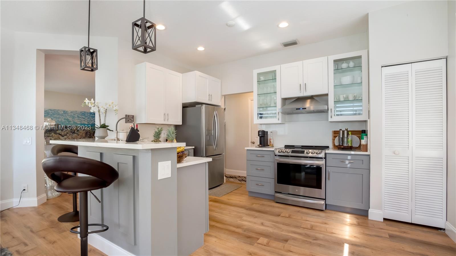 675 Falling Water Road Weston, FL 33326 - Photo 17 of 39 a kitchen with stainless steel appliances granite countertop a stove a refrigerator a oven a sink a dining table and chairs with wooden floor