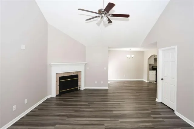 a view of an empty room with wooden floor fireplace and a window