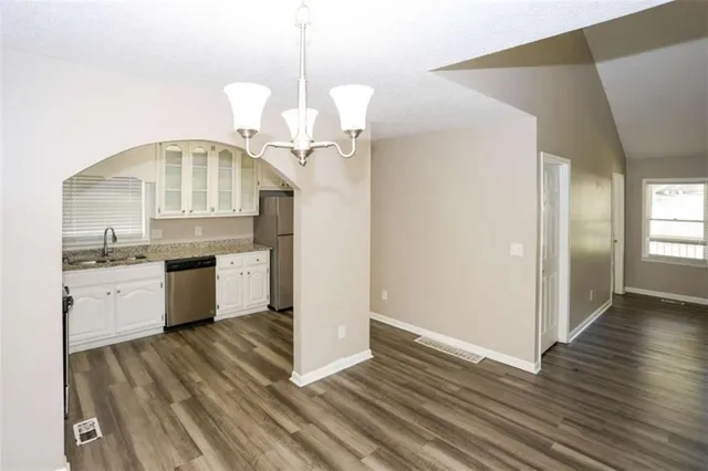 a large kitchen with a sink dishwasher a stove and a refrigerator with wooden floor