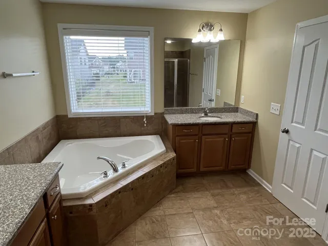 a bathroom with a granite countertop sink a mirror and shower